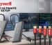 Honeywell docking stations, HDMI and DisplayPort cables, and a USB charger displayed in front of a multi-monitor workstation setup with the text ‘Honeywell – For the Ultimate Laptop Setup.